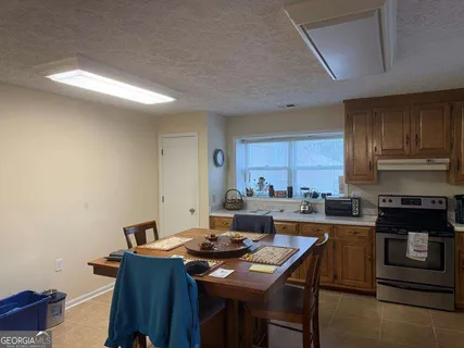 a kitchen with a stove a sink dishwasher a dining table and chairs with wooden floor