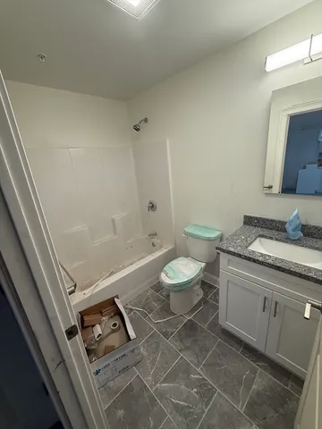 a bathroom with a granite countertop sink mirror vanity and toilet