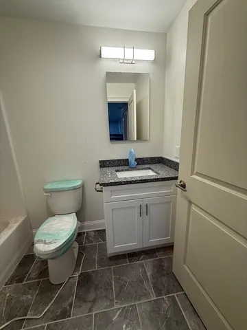 a bathroom with a granite countertop toilet and a sink