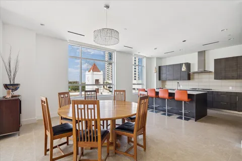 a kitchen with stainless steel appliances granite countertop a stove top oven a sink dishwasher a dining table and chairs with wooden floor