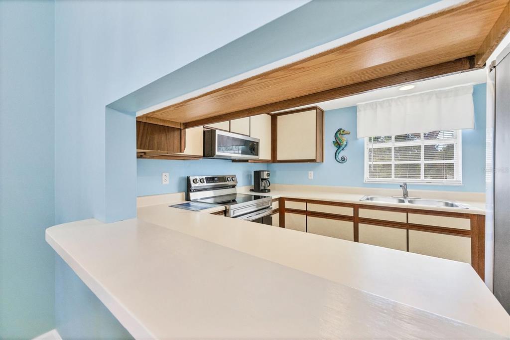 1531 Placida Road, Unit 202 Englewood, FL 34223 - Photo 13 of 44 a kitchen with stainless steel appliances a stove a sink and a microwave