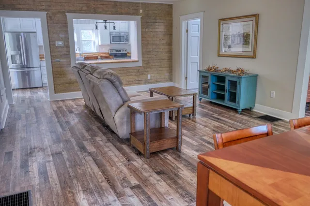 a kitchen with stainless steel appliances granite countertop a refrigerator a sink dishwasher a stove and white countertops with wooden floor