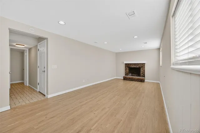 a view of empty room with wooden floor and fireplace