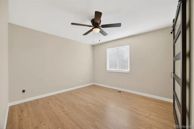 a view of empty room with wooden floor and fan