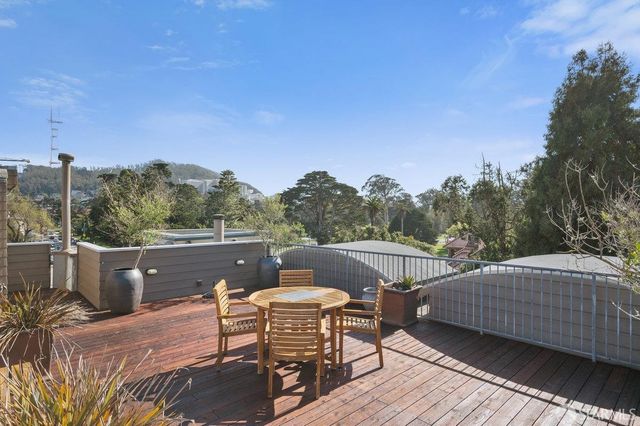a view of a roof deck with table and chairs a barbeque with wooden floor and fence