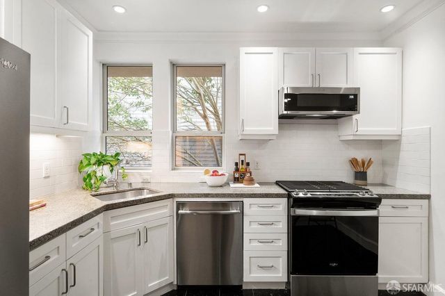 a kitchen with stainless steel appliances a white stove top oven sink and cabinets