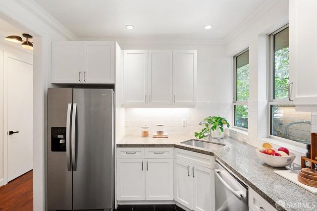 a kitchen with granite countertop a white cabinets and window