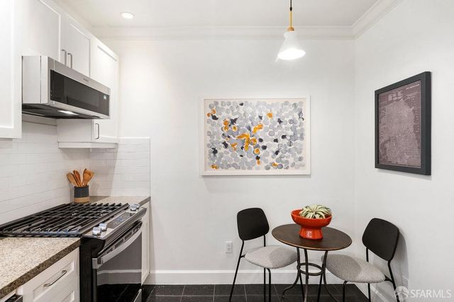 a kitchen with stainless steel appliances granite countertop a stove a microwave a dining table and chairs with wooden floor