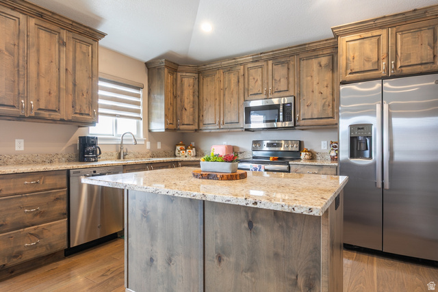 1228 North Providence Way Tooele, UT 84074 - Photo 8 of 28 Kitchen featuring a central island with a light-toned countertop, wood-finish cabinetry, stainless steel appliances, and a window with horizontal blinds