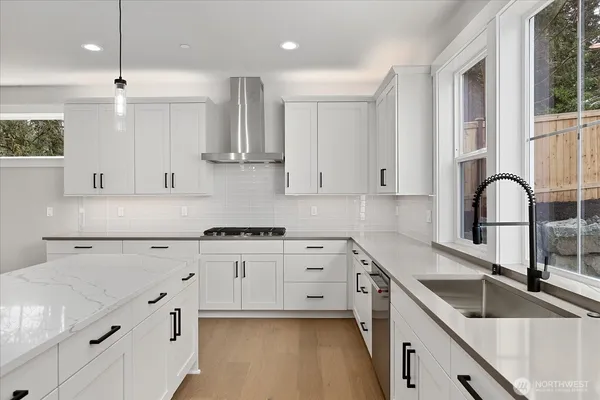 a kitchen with granite countertop a sink stainless steel appliances and white cabinets