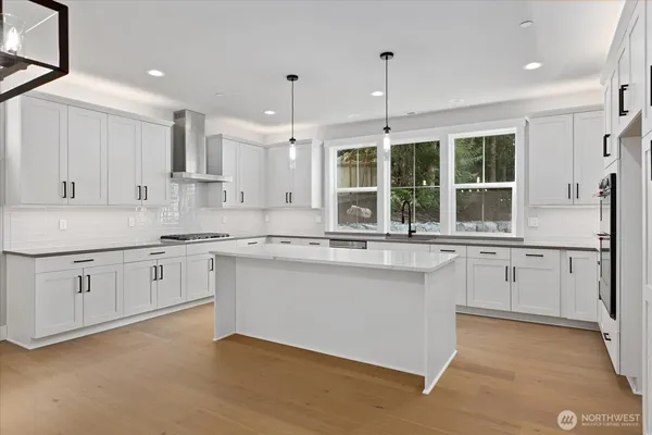 a kitchen that has a lot of white cabinets and wooden floor