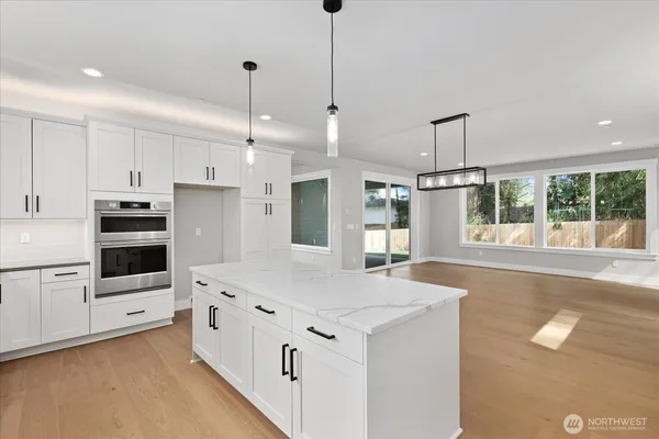 a kitchen with stainless steel appliances kitchen island granite countertop a stove a sink and a refrigerator with white cabinets