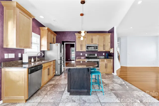 a kitchen with stainless steel appliances granite countertop a stove a refrigerator a oven a sink with a dining table and chairs