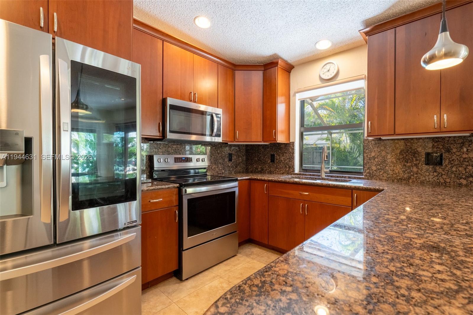 10116 Southwest 144th Place Miami, FL 33186 - Photo 11 of 28 a kitchen with stainless steel appliances granite countertop a stove a sink and a microwave