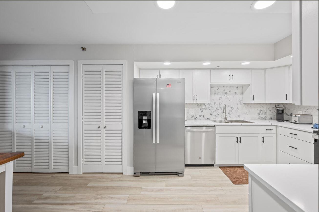 500 Ocean Trail Way, Unit 506 Jupiter, FL 33477 - Photo 5 of 28 a kitchen with stainless steel appliances white cabinets and wooden floor