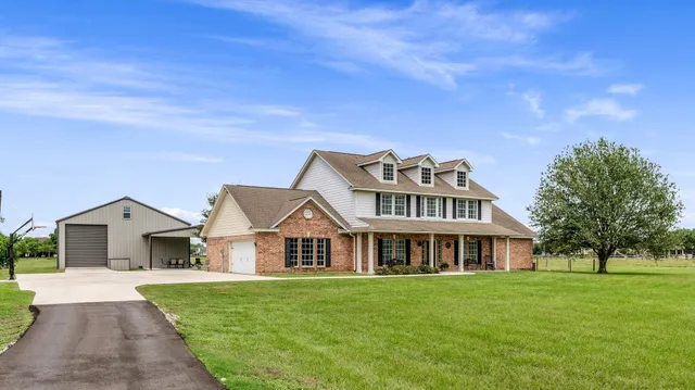 a view of a house with a big yard and large trees