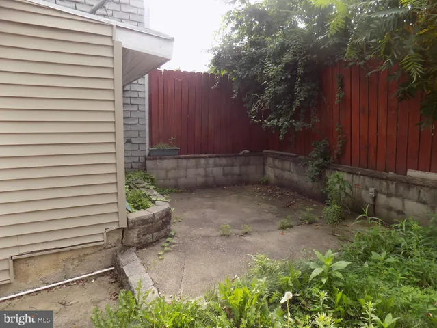 a view of a backyard with plants and wooden fence