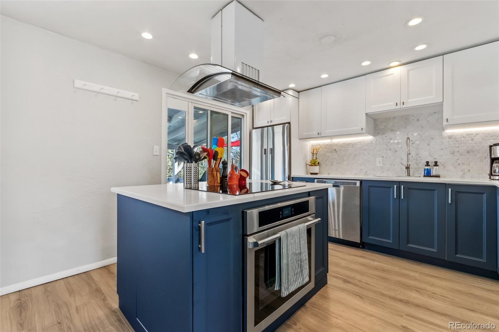 a kitchen with stainless steel appliances a sink and wooden floor