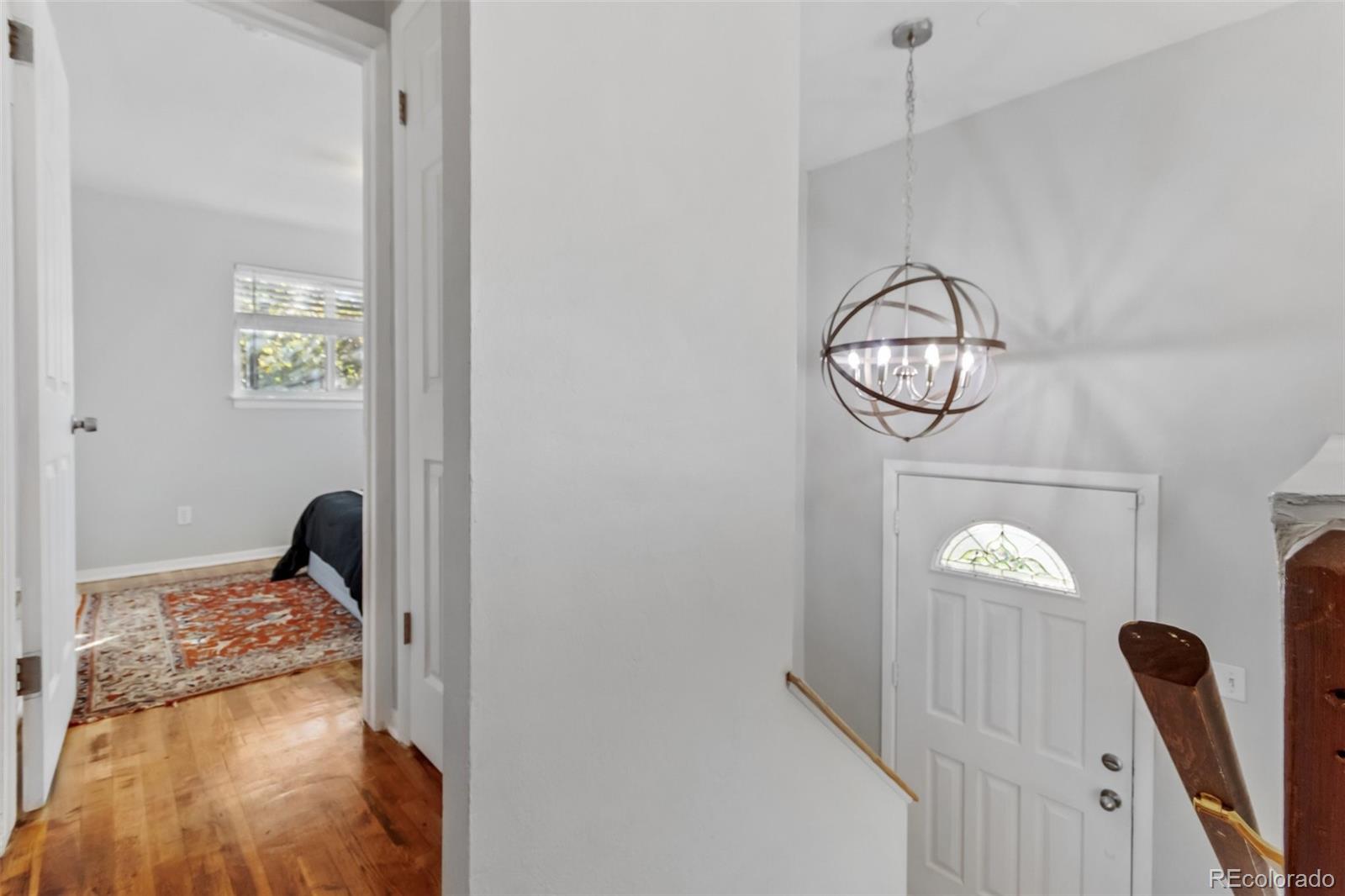 13436 Fitzsimons Way Aurora, CO 80011 - Photo 24 of 40 a view of a hallway with wooden floor and a chandelier