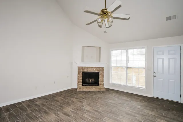 an empty room with chandelier fan and windows