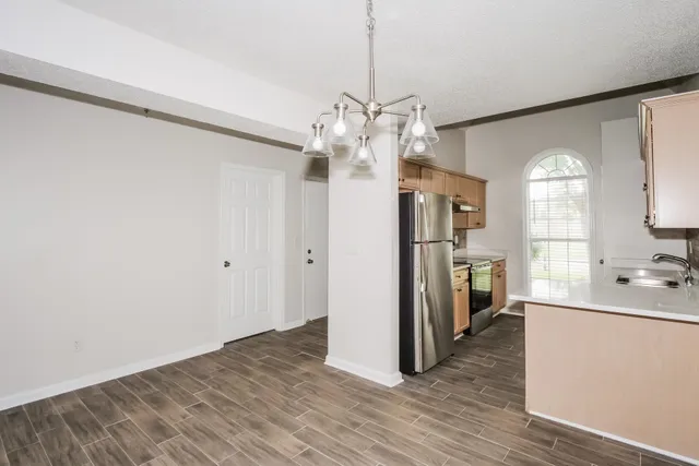 a view of a kitchen with a sink refrigerator and wooden floor