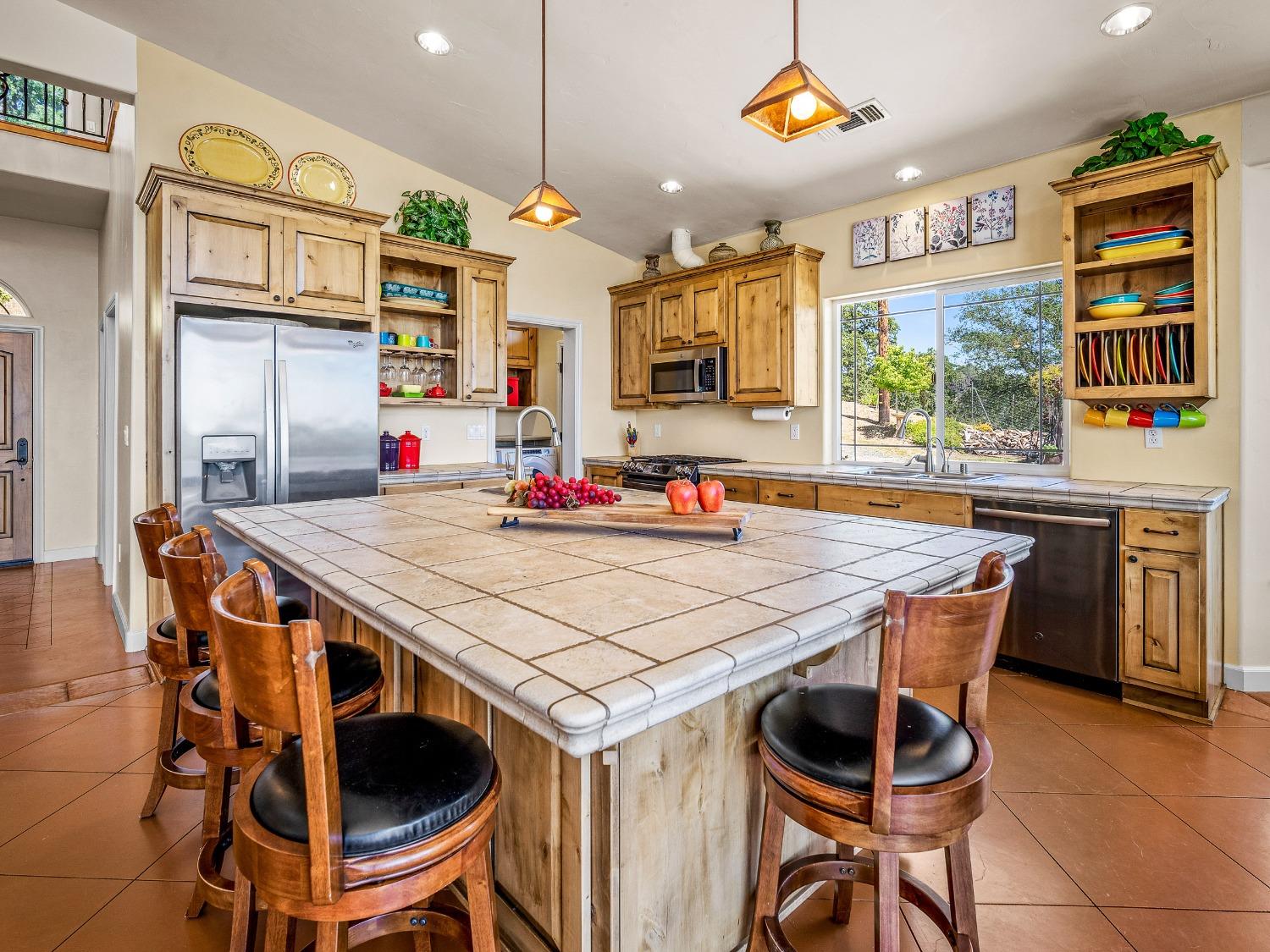 6801 Sagittarius Road Placerville, CA 95667 - Photo 10 of 34 a open kitchen with stainless steel appliances kitchen island granite countertop a table chairs in it and wooden floors