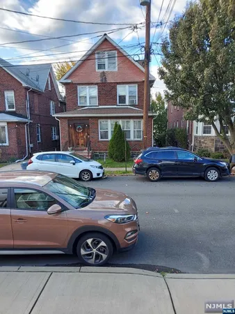 a front view of a house with cars parked on the roadside