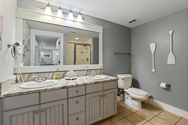 a bathroom with a double vanity sink toilet and mirror