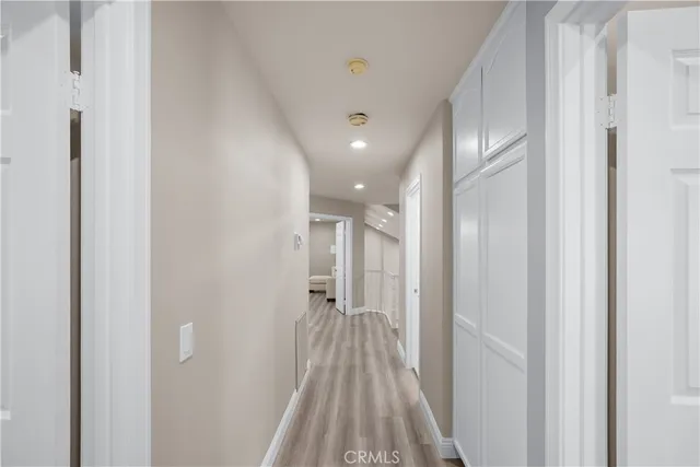 a view of a hallway with wooden floor and a bathroom