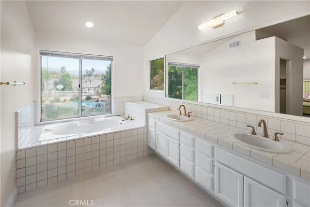 a spacious bathroom with a double vanity sink a large mirror and a bathtub