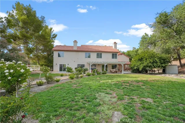 a front view of a house with a garden and trees