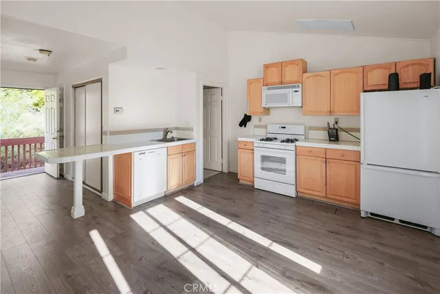 a kitchen with a stove a refrigerator and a view of living room