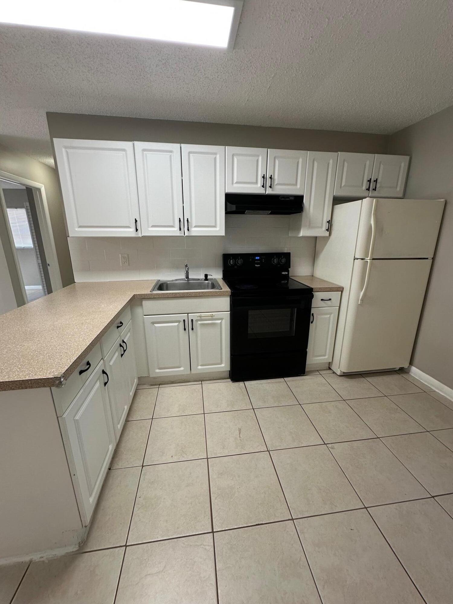 4810 Davis Road, Unit 4814 Lake Worth, FL 33461 - Photo 5 of 14 a kitchen with a sink a stove a refrigerator and cabinets