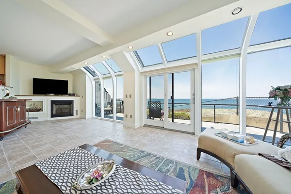 a living room with furniture floor to ceiling window and a flat screen tv