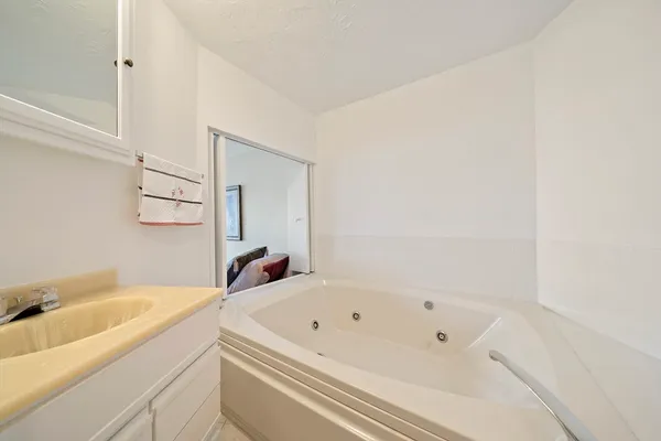 a bathroom with a tub sink and mirror