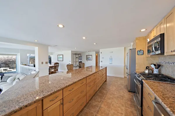 a large kitchen with granite countertop a large counter top cabinets and stainless steel appliances