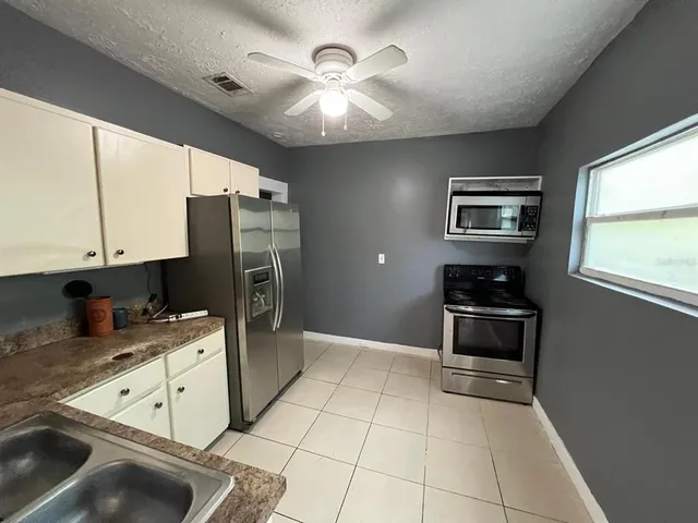 a kitchen with stainless steel appliances granite countertop a refrigerator a stove a sink a chimney and furniture