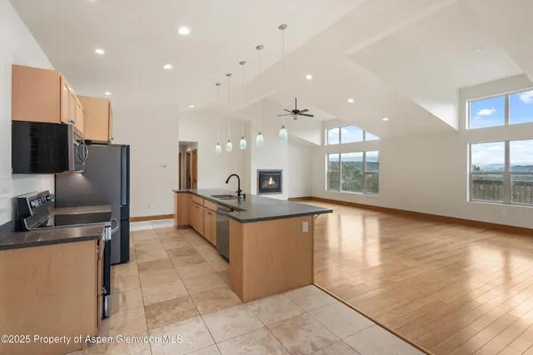 a large kitchen with stainless steel appliances a large counter top a stove a chimney a sink and a refrigerator