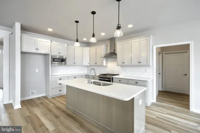 a kitchen with stainless steel appliances a sink a stove a refrigerator cabinets and a window