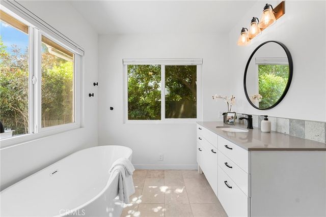 a bathroom with a tub a sink and a window