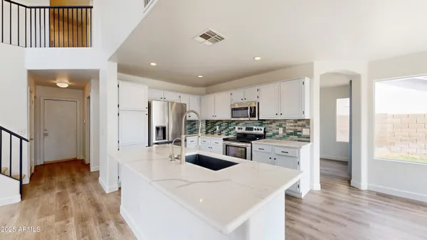 a kitchen with refrigerator a stove and white cabinets with wooden floor