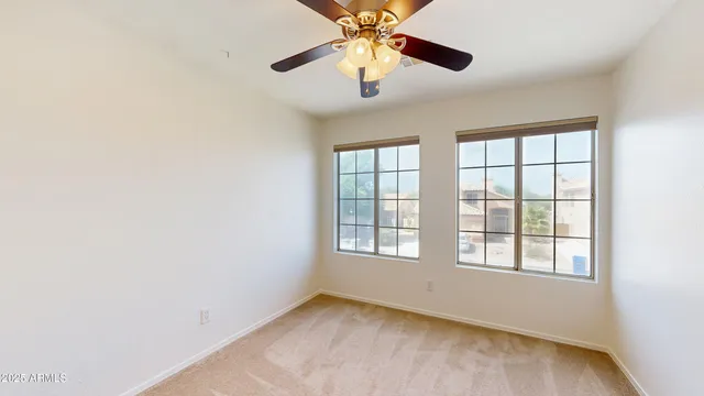 an empty room with windows and chandelier fan