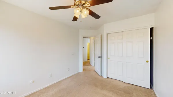 an empty room with closet and a chandelier fan