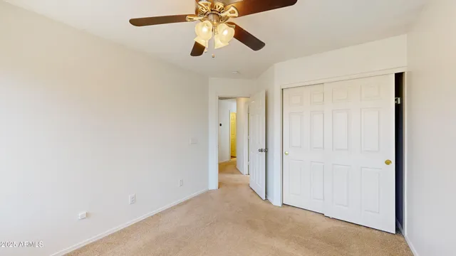 an empty room with closet and a chandelier fan