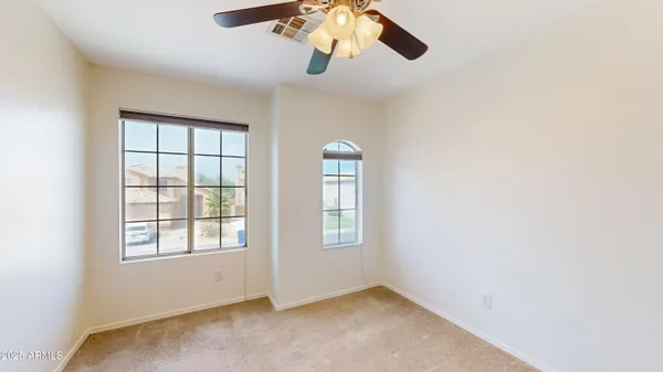 an empty room with windows and chandelier fan