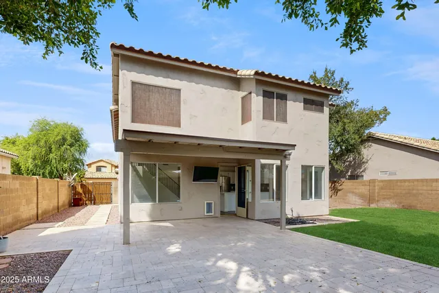 a view of a white house with a small yard and a large tree