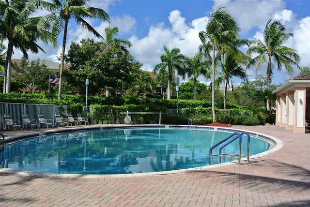 a view of a swimming pool with a yard and palm trees