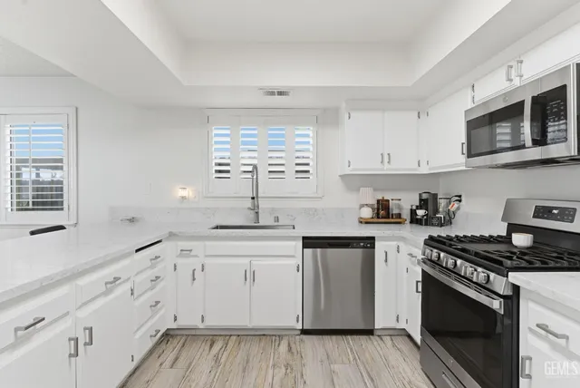 a kitchen with cabinets stainless steel appliances a sink and a window