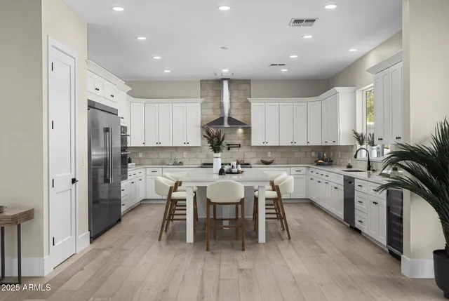 a kitchen with a sink dishwasher a dining table chairs refrigerator and cabinets