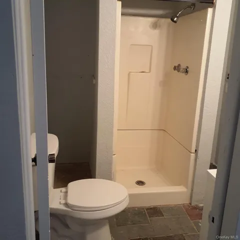 a bathroom with a granite countertop toilet a sink and shower